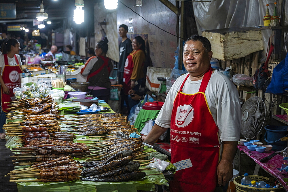 Man sells perfectly grilled fish skewers at the night market, Luang Prabang, Luang Prabang Province, Laos, Asia