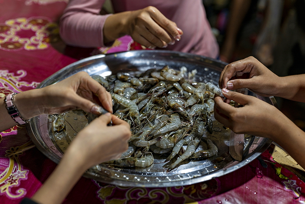 Hands of women peeling the prawns at a stall at the night market, Luang Prabang, Luang Prabang Province, Laos, Asia