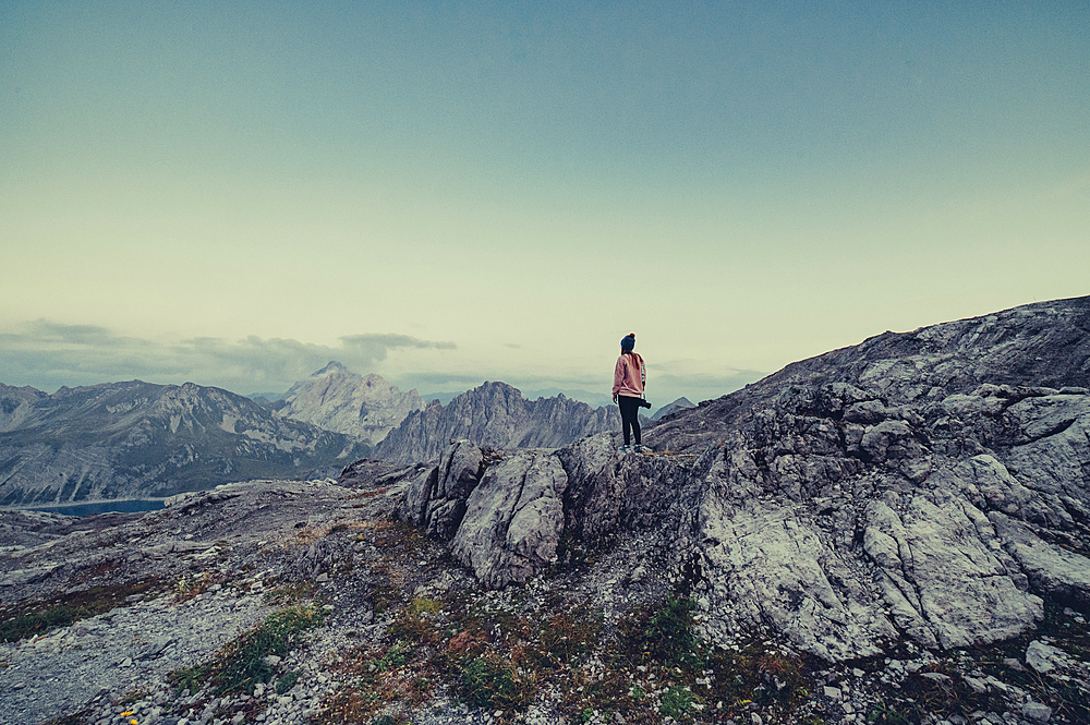 Woman with camera stands on a mountain near Lünersee, Vorarlberg, Austria, Europe