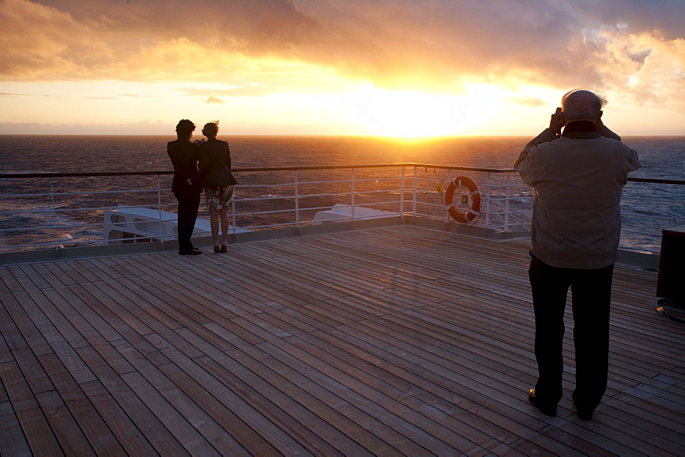 Young couple watching the sunset, Passenger on the afterdeck taking photographs, Cruise liner, Queen Mary 2, Transatlantic, Atlantic ocean