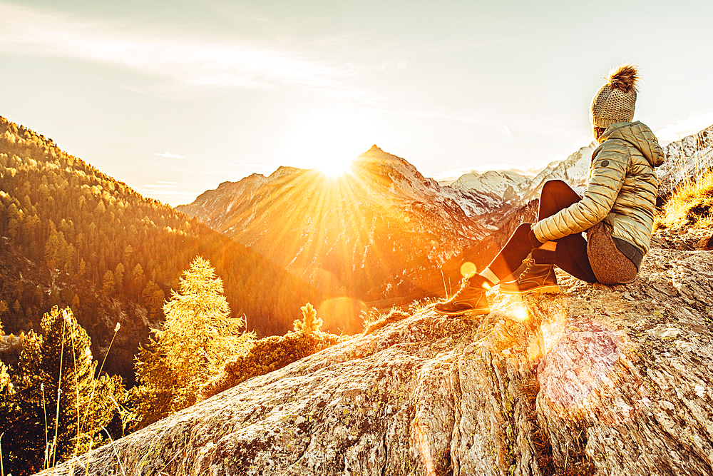 Woman sits on rocks in Maloja and enjoys the sunset, Engadin, Graubünden, Switzerland, Europe