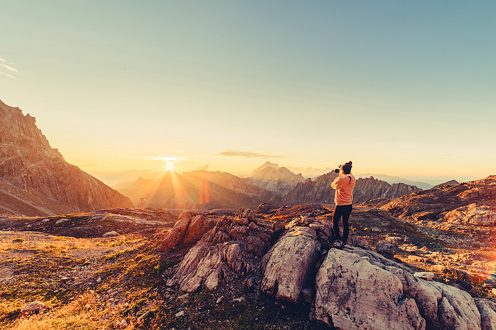 Woman with camera at sunrise in the mountains in Raetikon, Vorarlberg, Austria, Europe