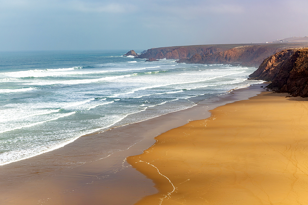 Waves breaking coastal cliffs and sandy beach, Plage Imin Turga, Mirleft, southern Morocco, north Africa