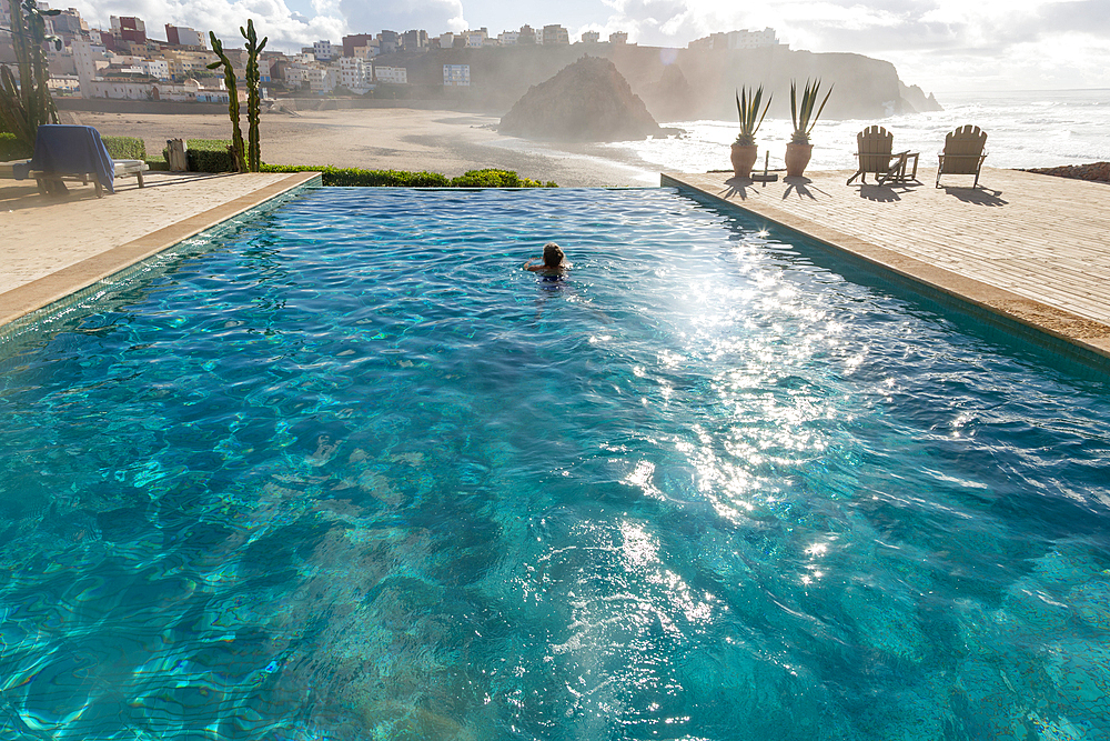 Woman swimming infinity pool by Atlantic Ocean, Hotel auberge Dar Najmat, Mirleft, Morocco, north Africa