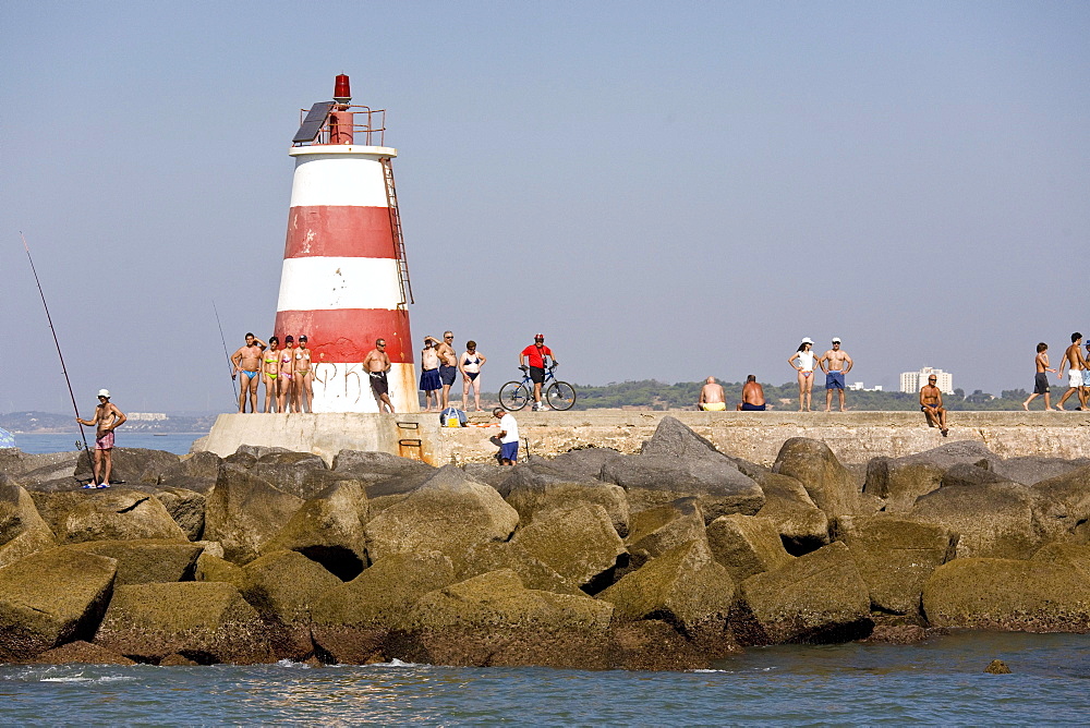 Tourists and fishermen at the lighthouse, Portimao beach, Portimao, Algarve, Portugal