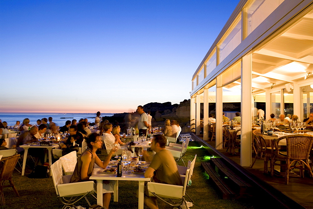 Tourists dining in a fish Restaurant on the beach at sunset, Praia do Evaristo, Albufeira, Algarve, Portugal