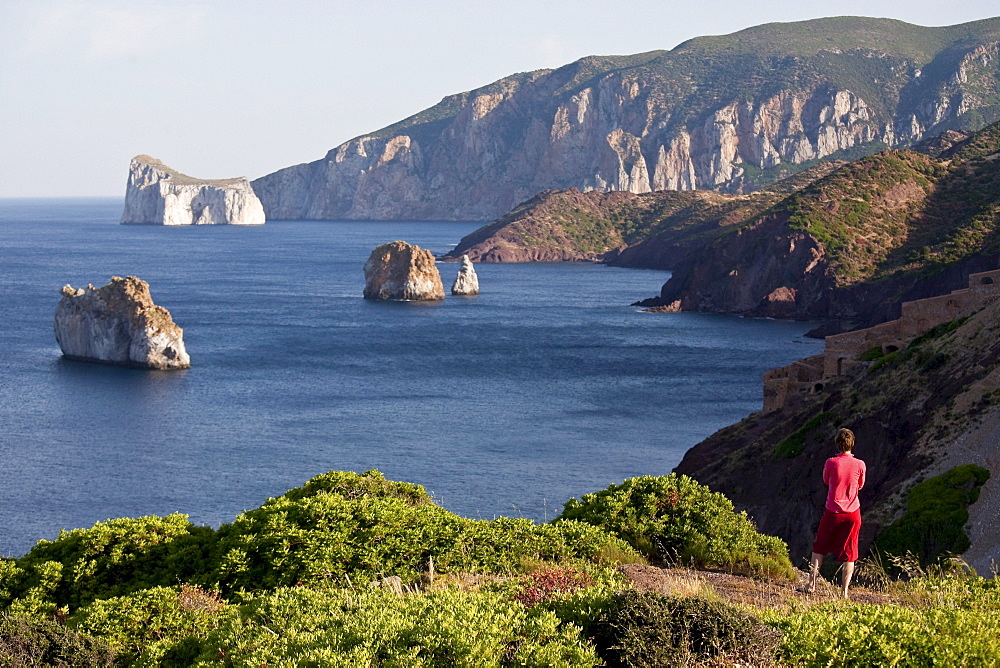 Pan di Zucchero, woman looking at rock off shore, Masua, Sardinia, Italy, Europe