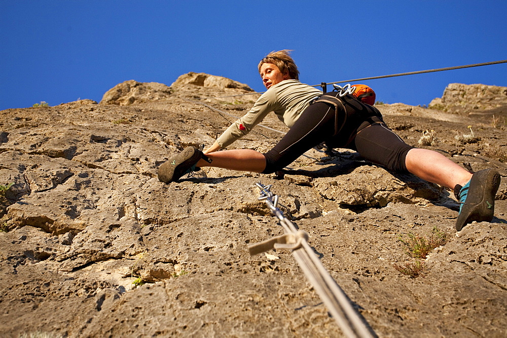 Young woman climbing up a sunlit rock face, Jerzu, Sardinia, Italy, Europe