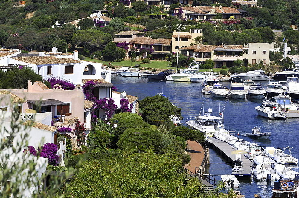 View at houses on the waterfront and boats at a jetty, Porto Cervo, North Sardinia, Italy, Europe