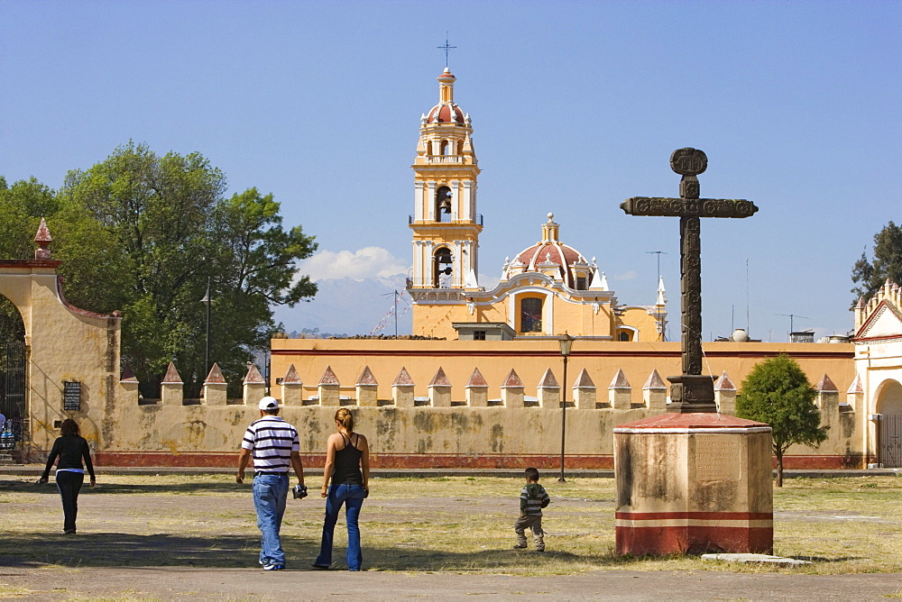 Family walking over the grounds of Ex-convento de San Gabriel in Cholula, the church of San Pedro is in the background, State of Puebla, Mexico