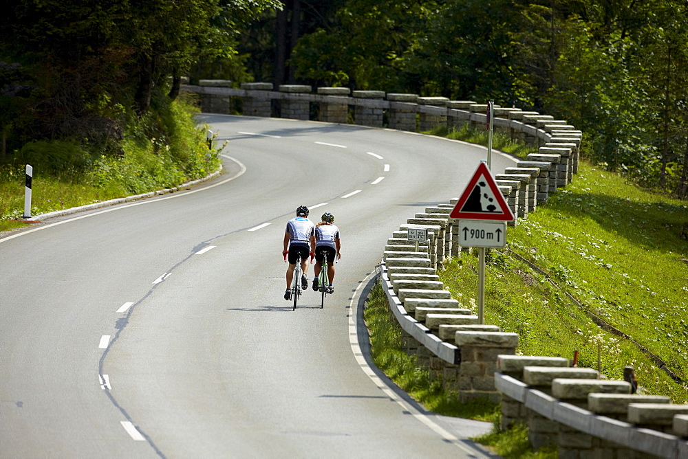 Two racing cyclists on bendy road, Spitzing, Bavaria, Germany