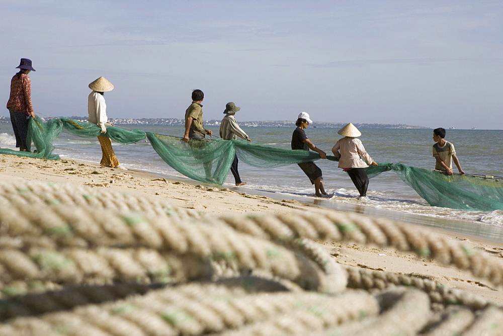 Fishermen with fishing net on the beach of Mui Ne, Binh Thuan Province, Asia