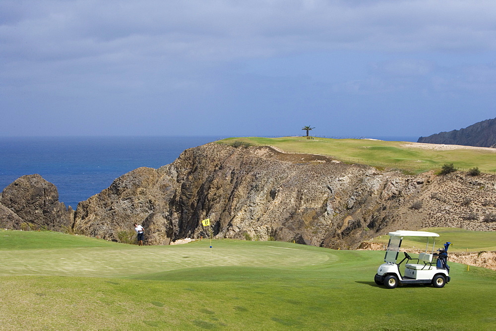 Golfer chipping ball from the green of Hole 15 at Porto Santo Golfe Golf Course, Porto Santo, near Madeira, Portugal