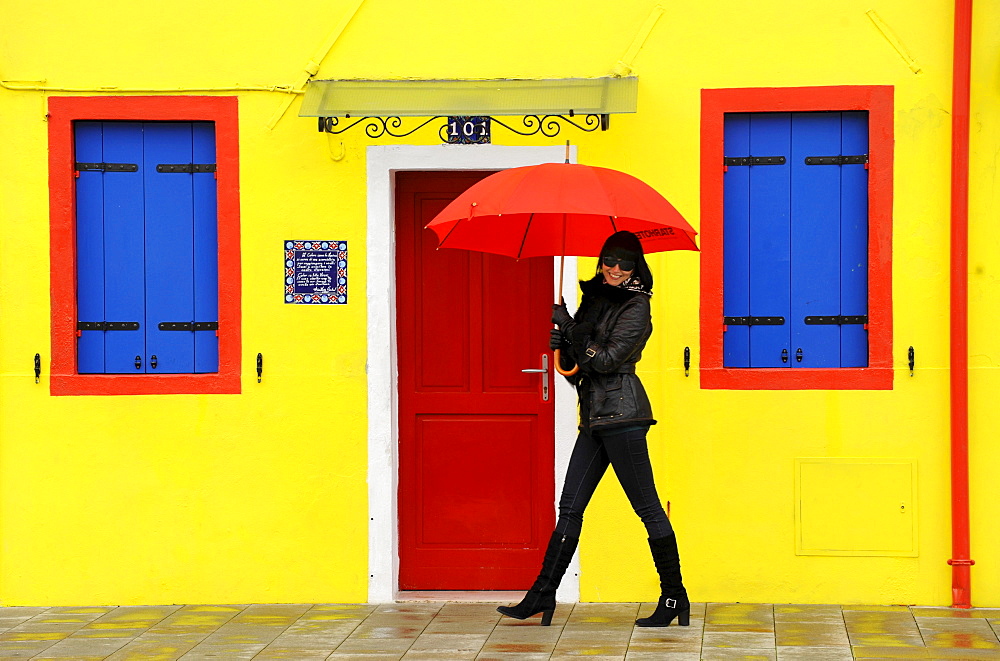 Woman with umbrella walking along the street, Burano, Venice, Veneto, Italy