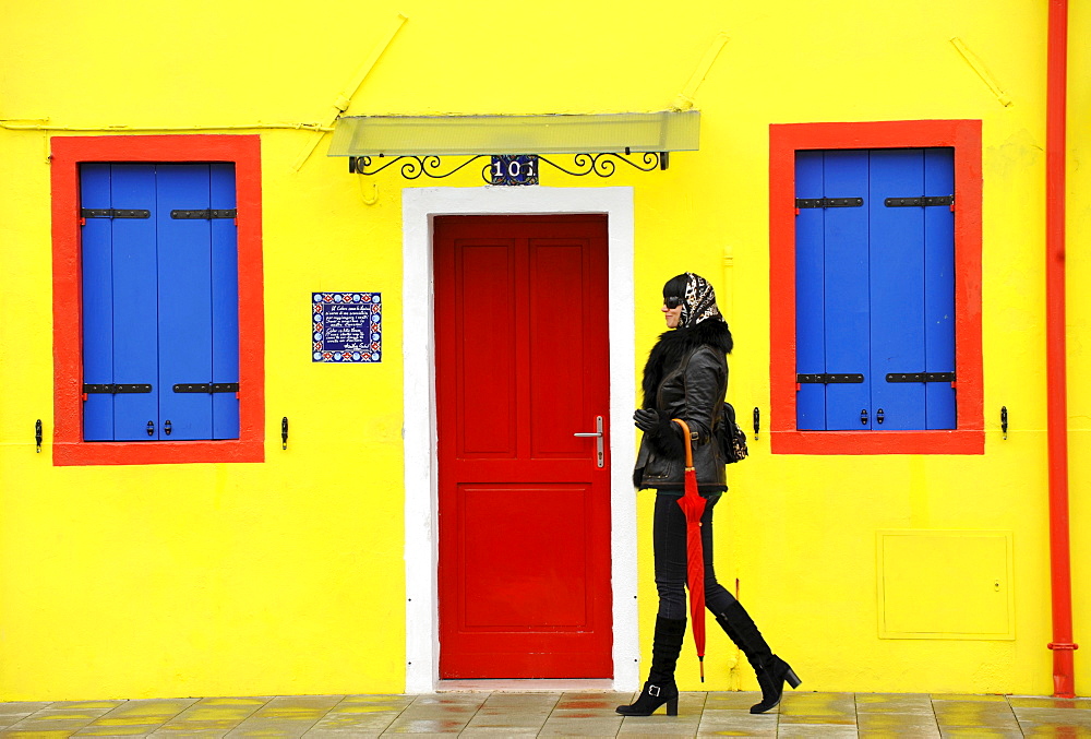 Young woman walking along the street, Burano, Venice, Veneto, Italy