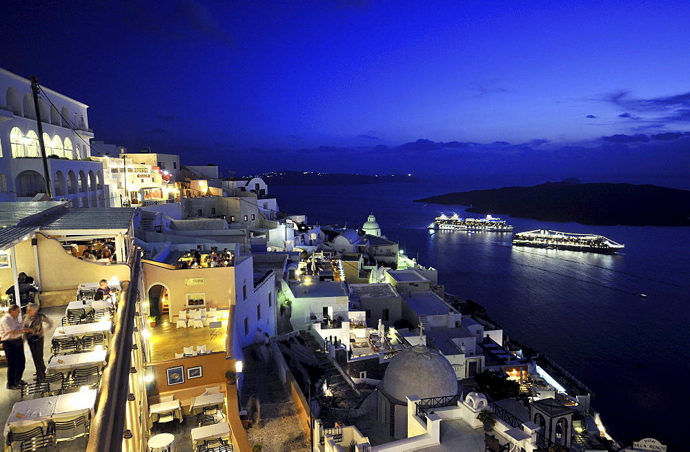Houses at the coast and illuminated ferries in the evening, Fira, Santorin, Cyclades, Greece, Europe