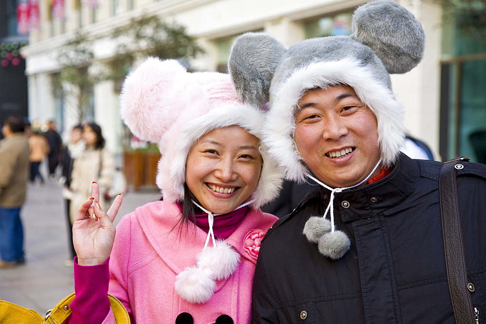 Portrait of a Chinese couple with funny winter hats in the shopping street Nanjing Lu, Shanghai, China, Asia