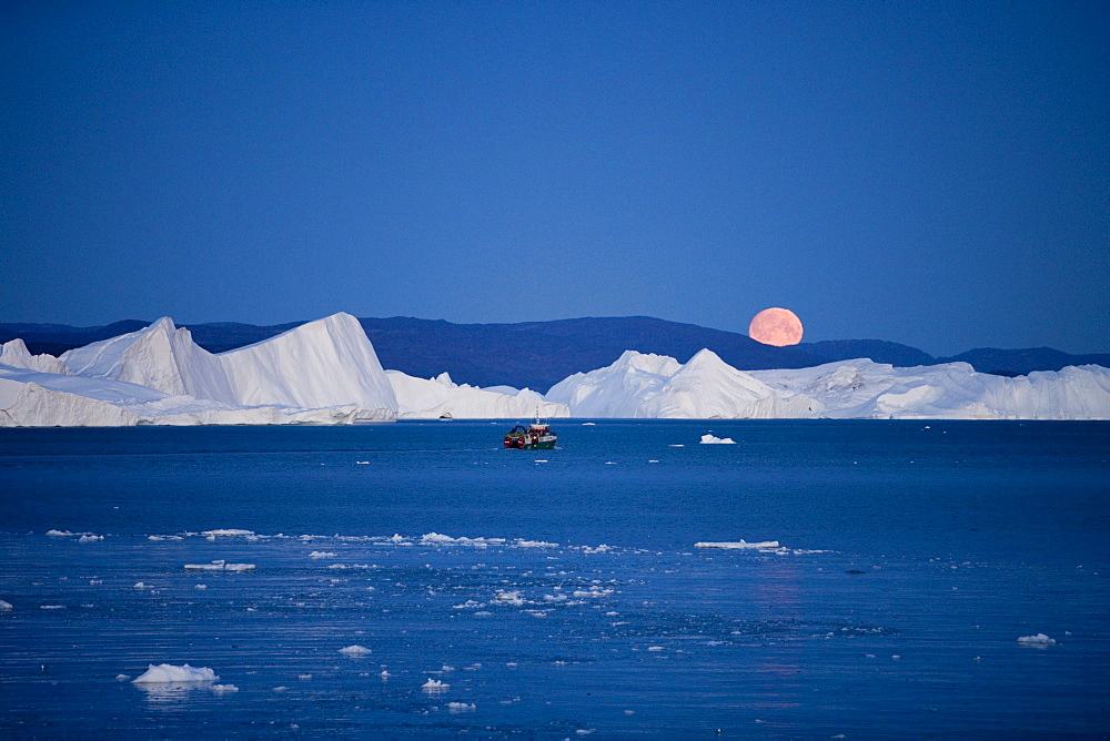 Full moon rising over icebergs from Ilulissat Kangerlua Icefjord at dusk, Ilulissat (Jakobshavn), Disko Bay, Kitaa, Greenland