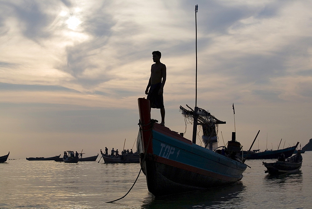 Man standing on a fishing boat in the sunset in Ngapali Beach, Gulf of Bengal, Rakhine State, Myanmar, Burma