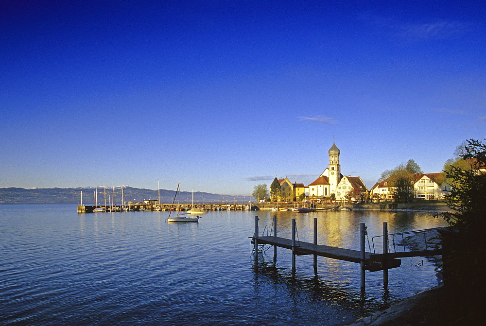 Church and castle at the lakeshore under blue sky, Wasserburg, Lake Constance, Bavaria, Germany