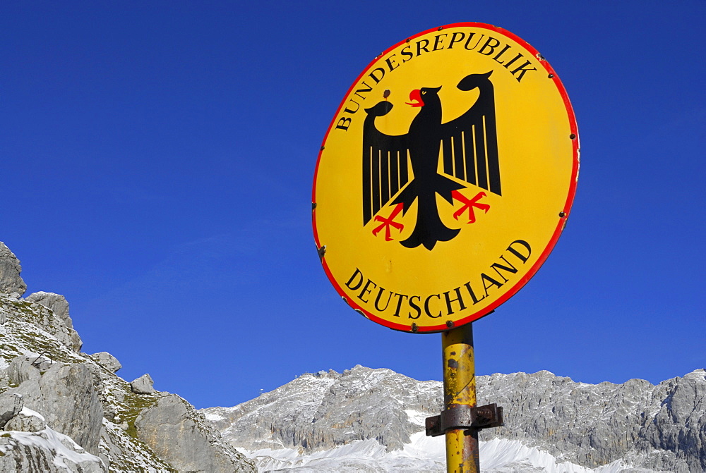 Sign of boarder Bundesrepublik Deutschland with Bundesadler at notch Gatterl with view to Zugspitze, Wetterstein range, Upper Bavaria, Bavaria, Germany