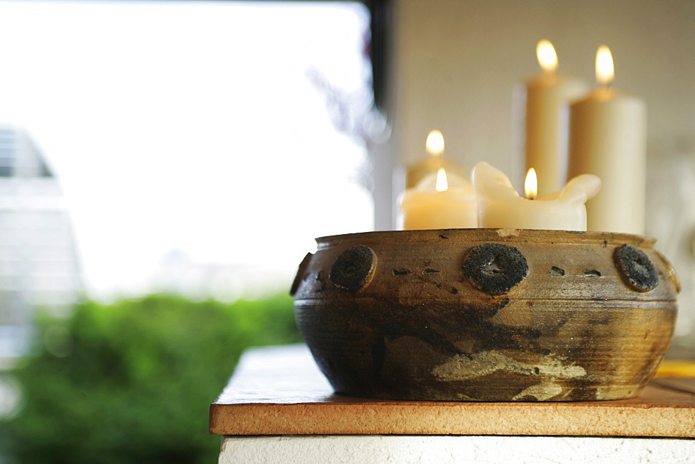 Lighted candles in a brown bowl