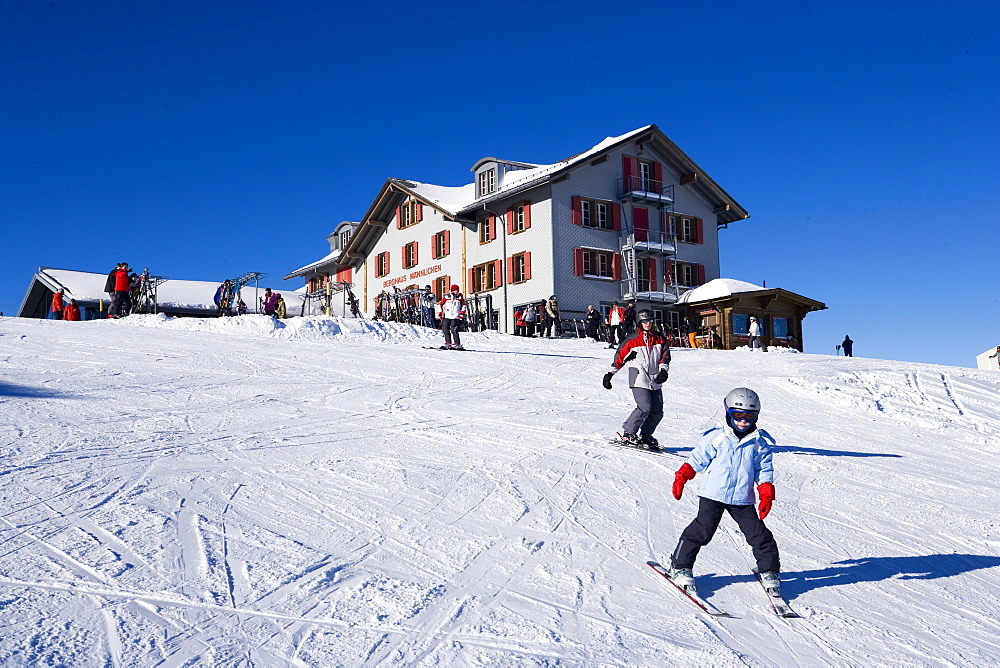 Skiers on slope, alpine lodge Maennlichen in background, Maennlichen, Grindelwald, Bernese Oberland, Canton of Bern, Switzerland