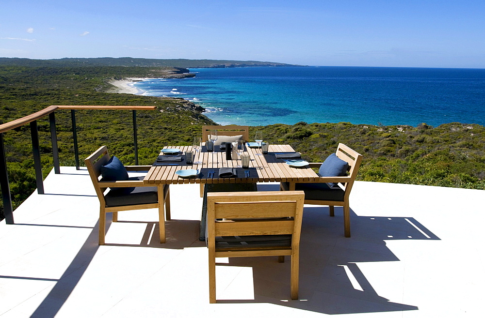 A table is laid at the terrace of the Southern Ocean Lodge in the sunlight, view at Hanson Bay, Kangaroo Island, South Australia, Australia