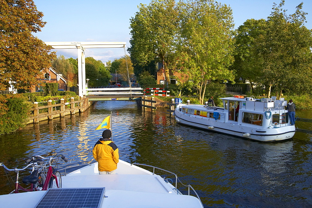 Two houseboats on the river Vecht approaching a bascule bridge, Netherlands, Europe