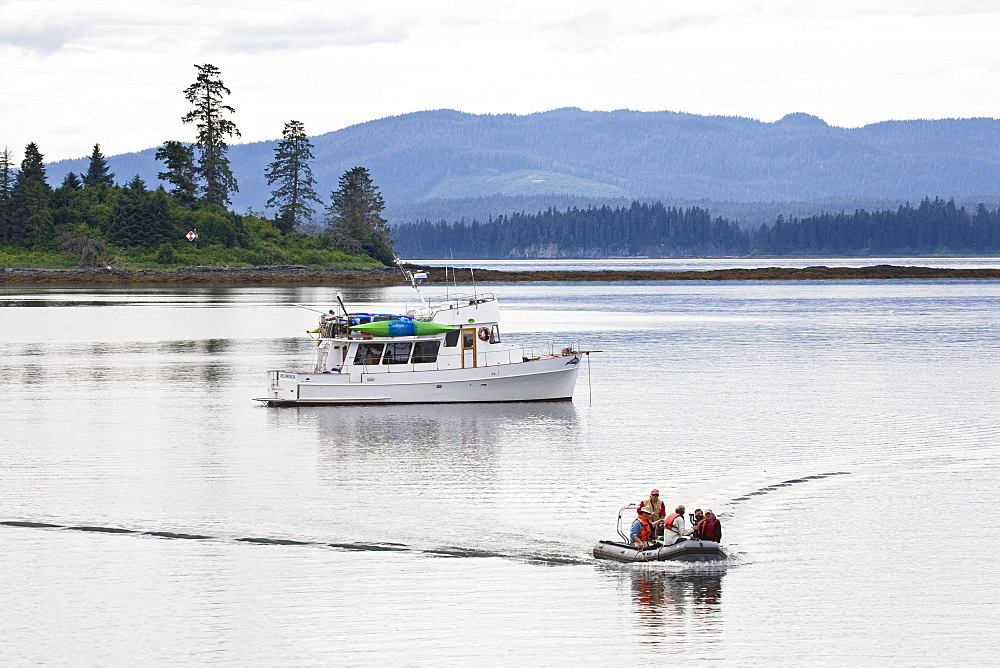 A motorboat and people in a dinghy, Inside Passage, Southeast Alaska, USA