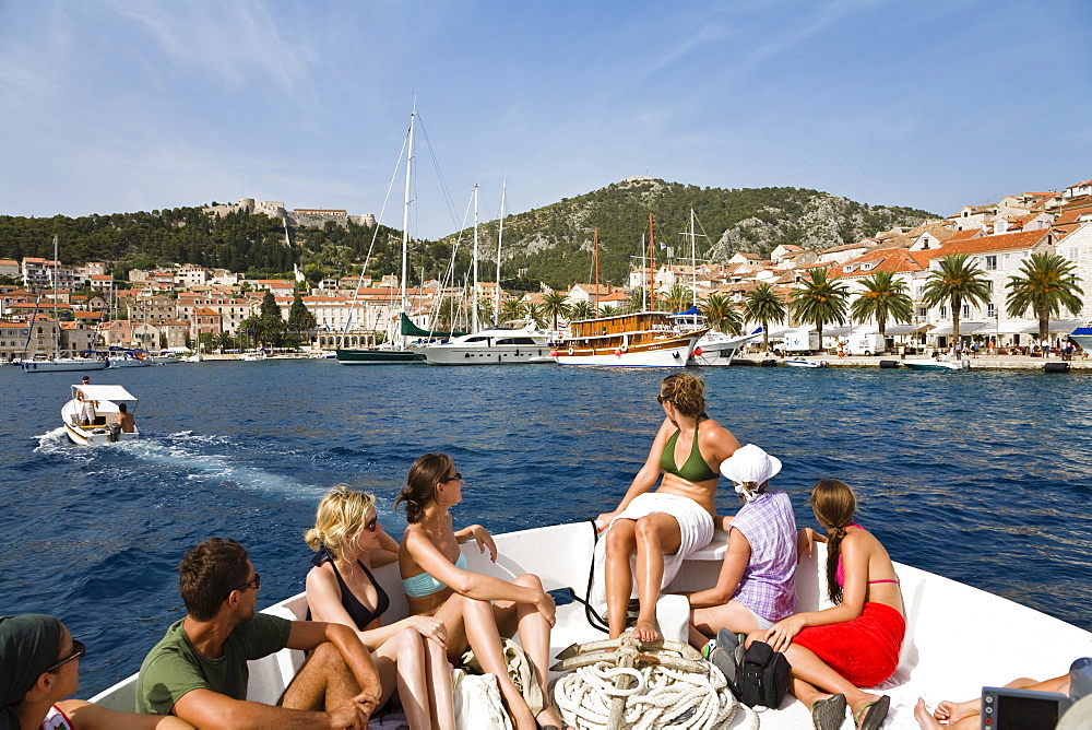 Tourists sitting in the bow of a boat with view at Hvar, Dalmatia, Croatia, Europe