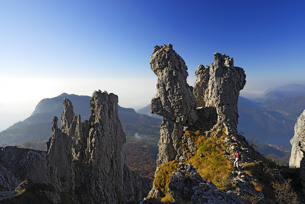 Woman hiking between pinnacles of Grigne, Bergamo Alps, Como, Lombardy, Italy