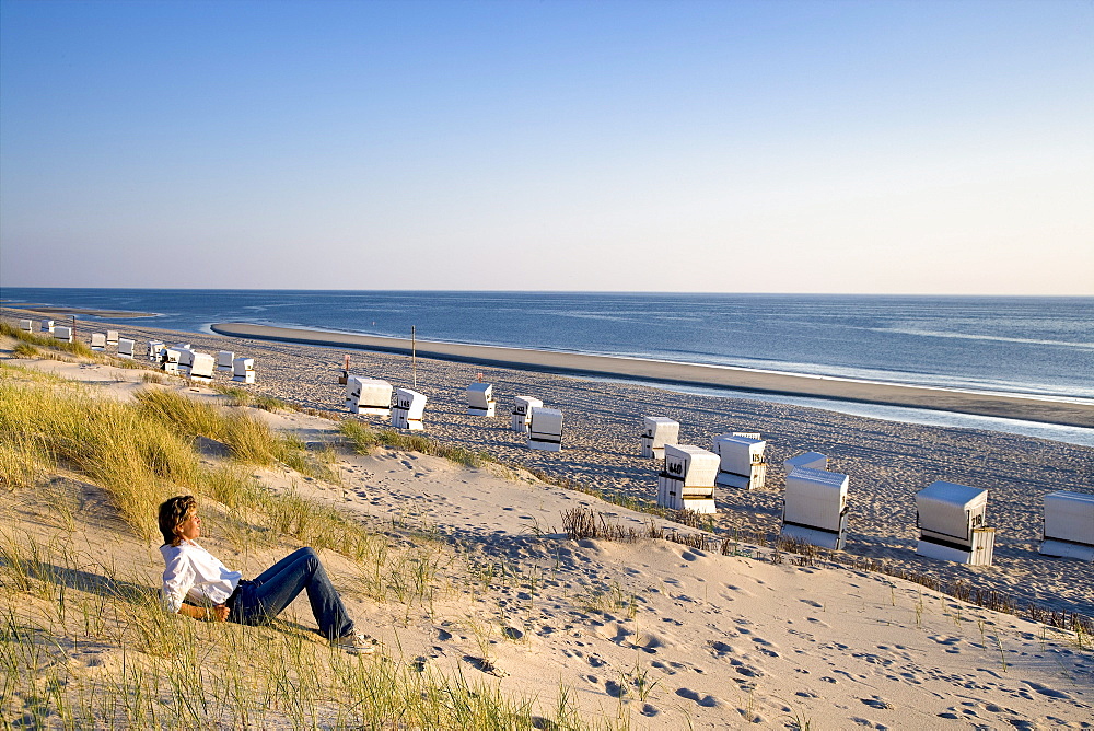 Woman sitting on beach, Rantum, Sylt Island, Schleswig-Holstein, Germany