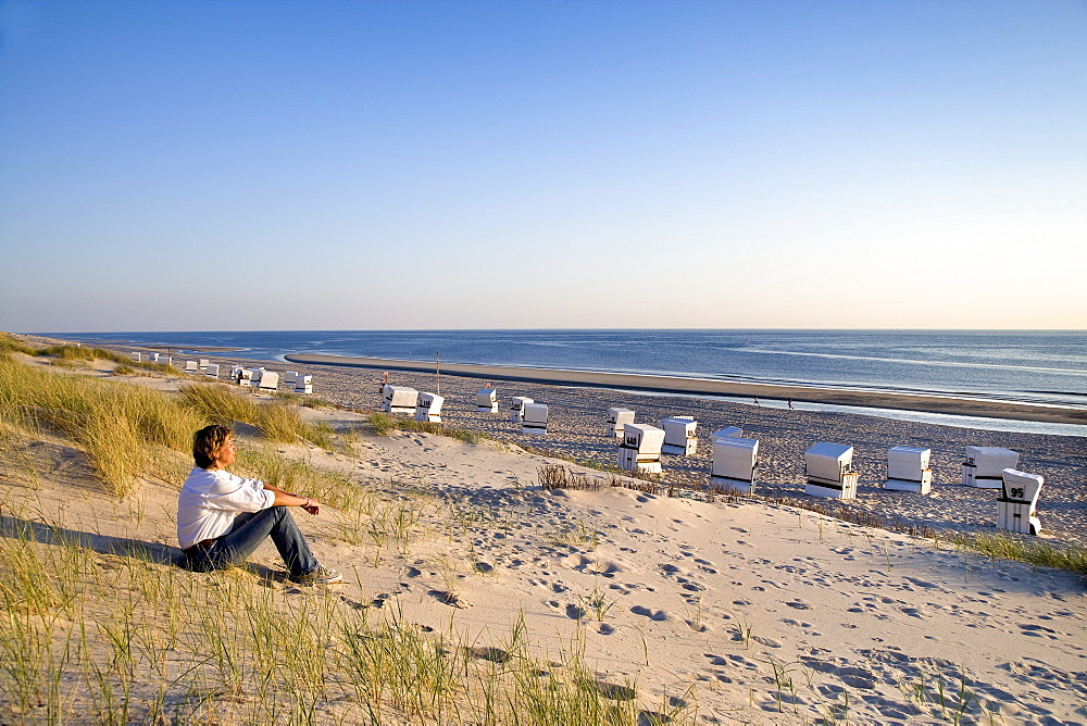 Woman sitting on beach, Rantum, Sylt Island, Schleswig-Holstein, Germany