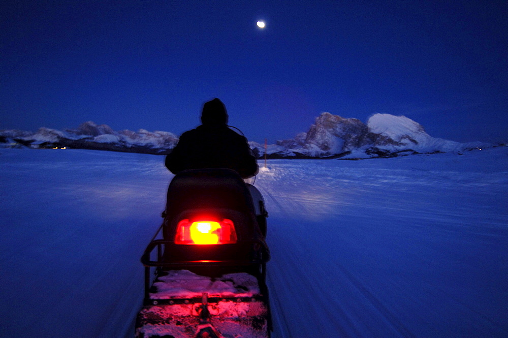 Man on a skidoo at night, Langkofel Mountain Range, South Tyrol, Italy