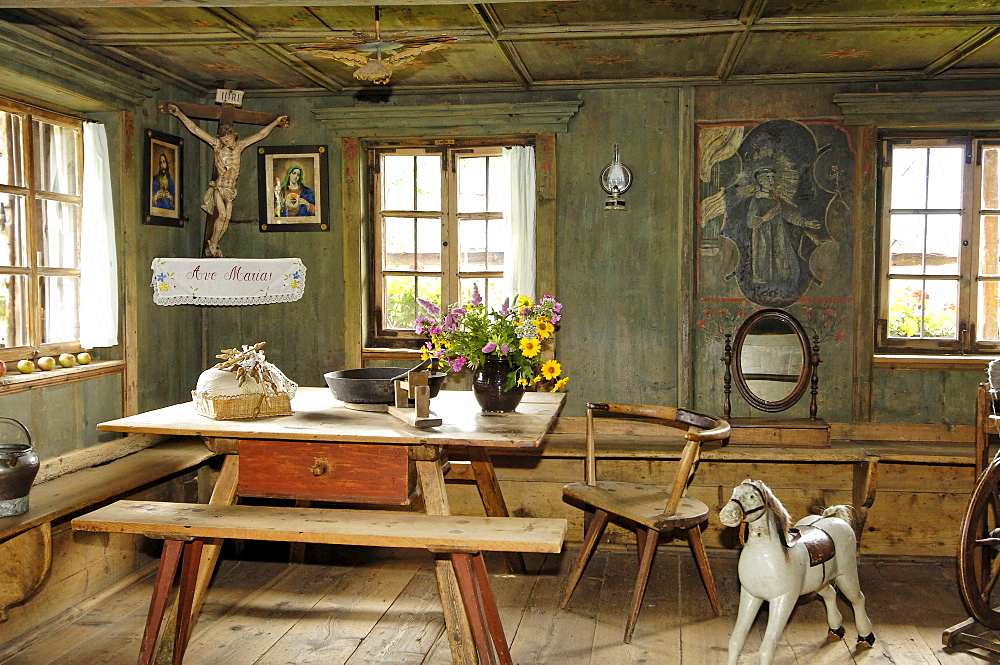 View inside the farmhouse with wooden bench, table and rocking horse, South Tyrolean local history museum at Dietenheim, Puster Valley, South Tyrol, Italy