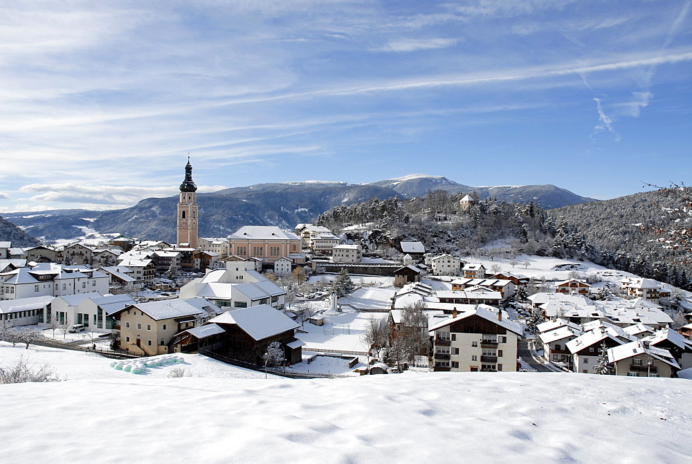 Snow covered houses and church of the village Kastelruth in the sunlight, South Tyrol, Italy, Europe
