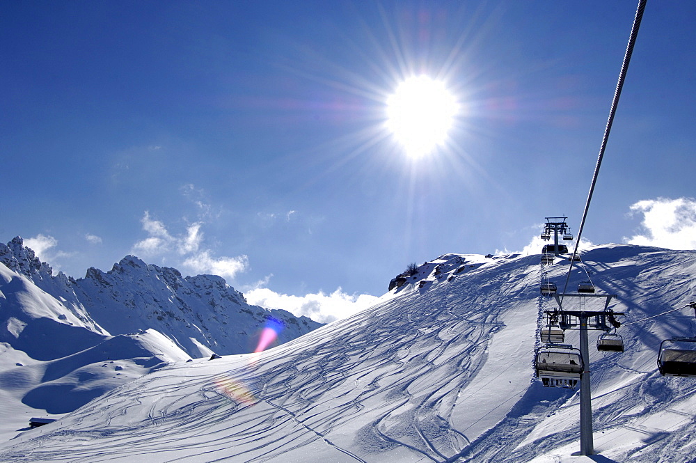 Chair lift in front of snow covered mountains in the sunlight, Dolomites, South Tyrol, Italy, Europe