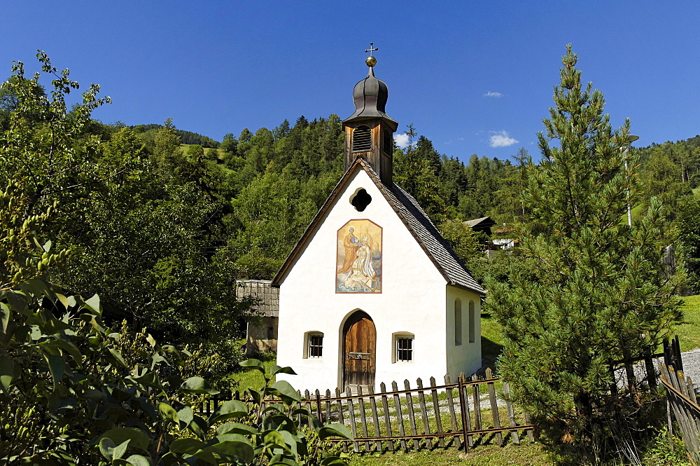 Chapel with wall painting between trees in the sunlight, Villnoess, Valle Isarco, South Tyrol, Italy, Europe