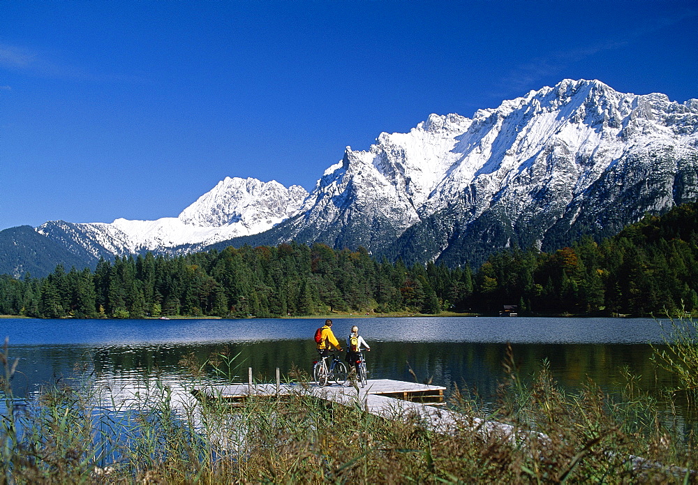 Couple with bikes on a jetty at lake Lautersee, Bavaria, Germany, Europe