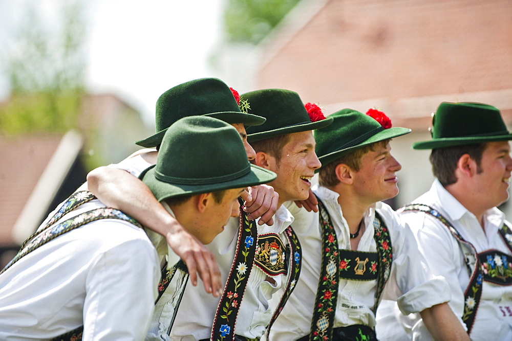 Young men wearing traditional costumes sitting side by side, May Running, Antdorf, Upper Bavaria, Germany