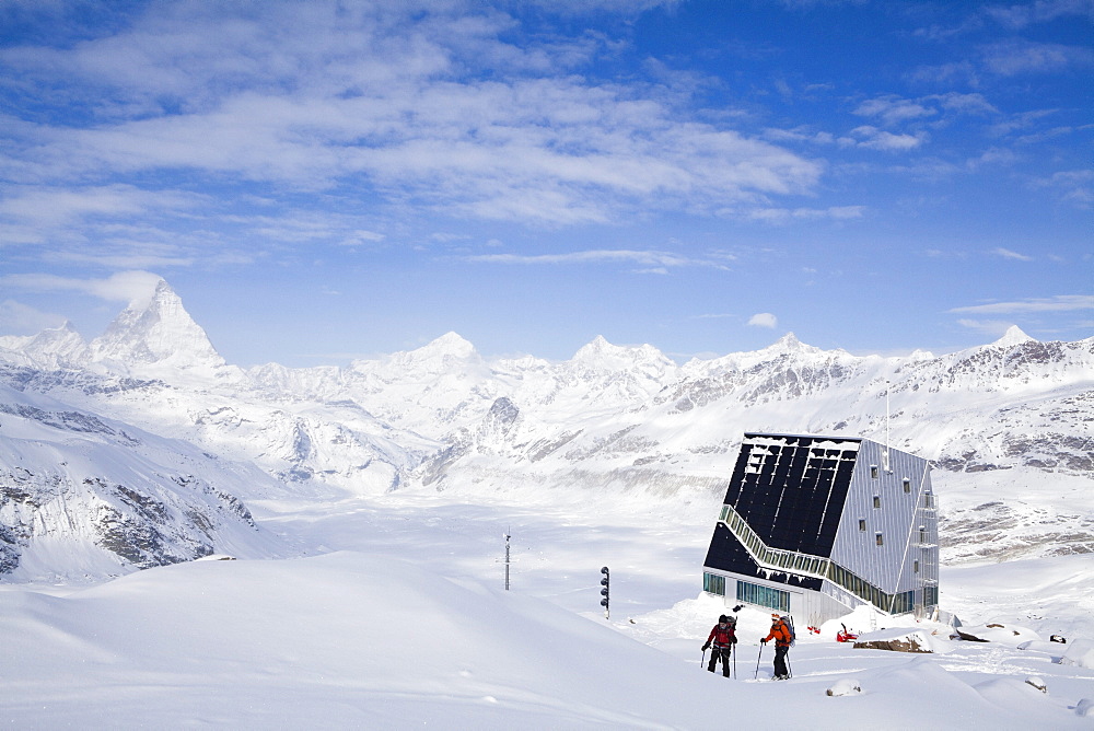 Two female back country skiers, Monte Rosa Hut in background, Canton of Valais, Switzerland