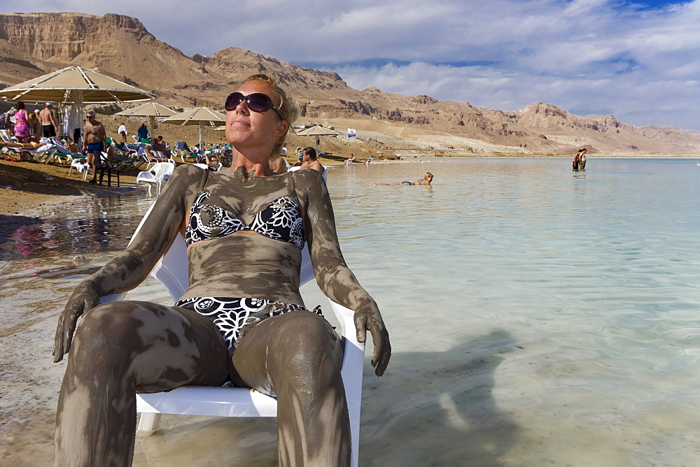 Woman smeared with mineral mud sunbathing, Dead Sea, En Bokek, Israel, Middle East