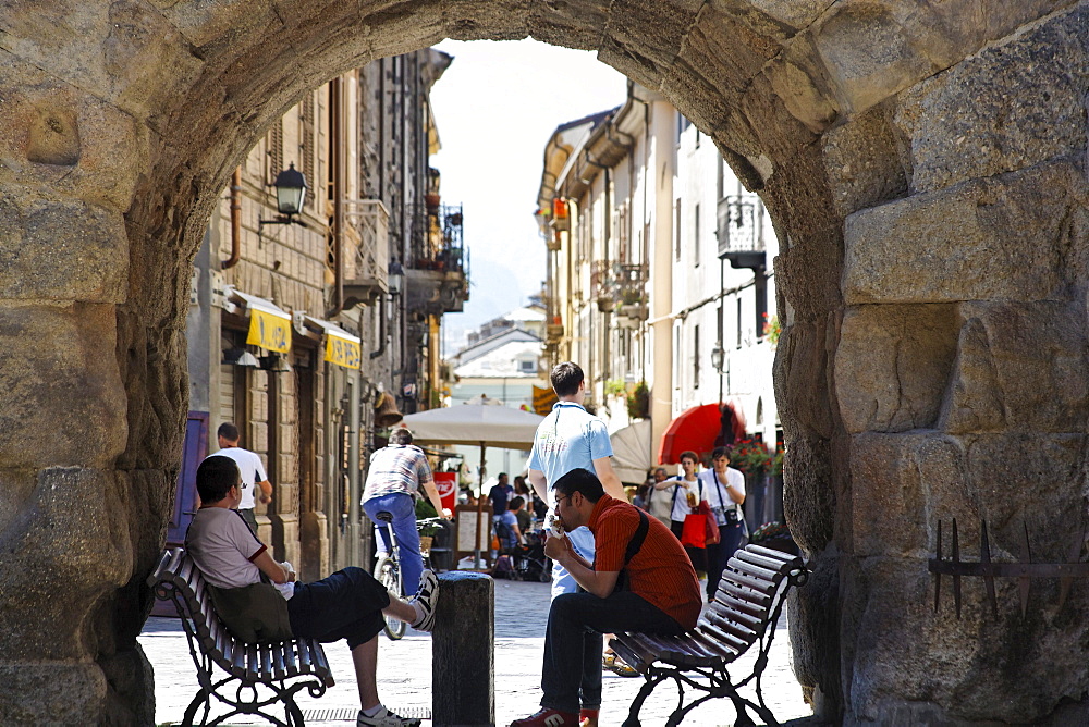 Two persons sitting in an archway, old town, Aosta, Aosta Valley, Italy