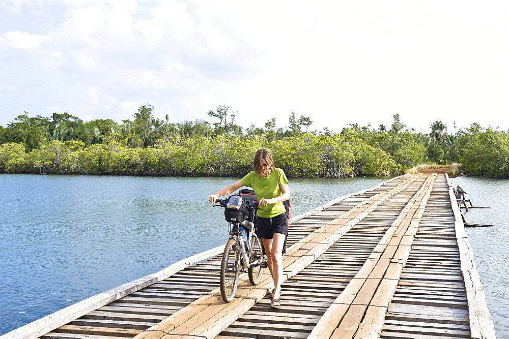 Woman is pushing her mountainbike in the masoala national park in madagaskar, africa