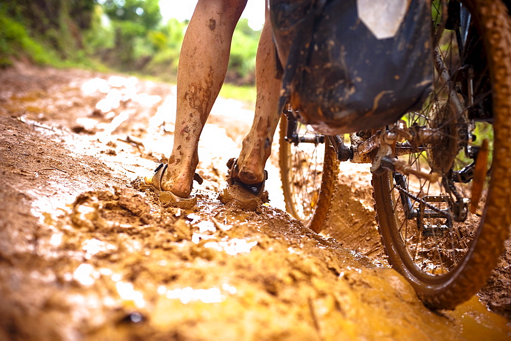 Woman pushing a mountainbike through mud, Masoala National Park, Madagascar