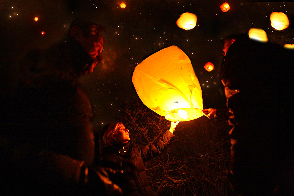 People lighting skylaterns on new year, Munsing, Bavaria, Germany