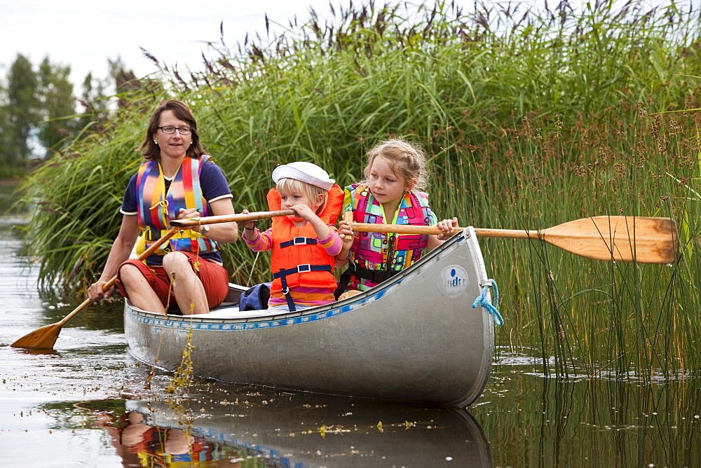 A woman and two girls in a canoe on the island of Norrbyskaer, Vaesterbotten, Sweden, Europe