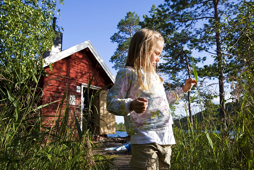 Girl in front of small cottage at the lake Taernaettvatten, national park Skuleskogen, Hoega Kusten, Vaesternorrland, Sweden, Europe