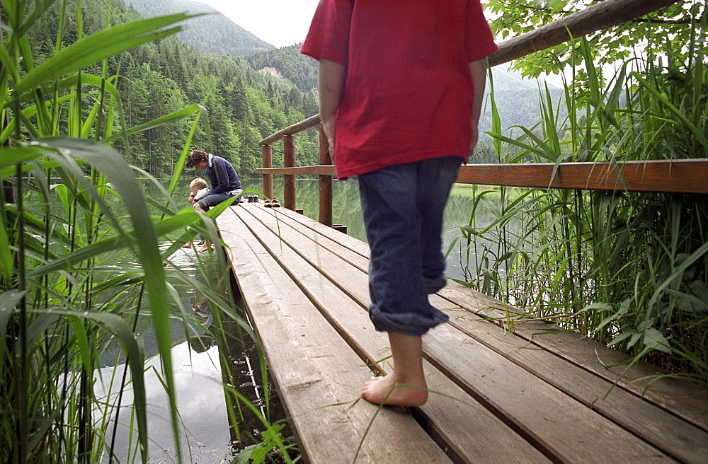 A little girl walking along a wooden platform on a lake, Schaffner Weiher, Stodertal, Austria, Alps, Europe